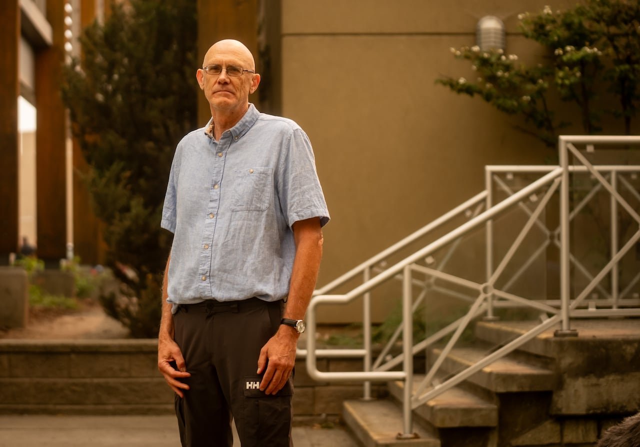 A man with a blue shirt in smoky surroundings.