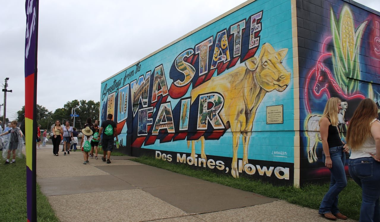 default-408 A colourful mural on the side of a building. The mural features a golden cow and the text "Greetings from the Iowa State Fair."
